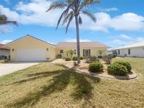 Charming single-story home featuring lush landscaping, a tile roof, and a two-car garage at 111 Englewood Garden Ct, Englewood, FL 34223