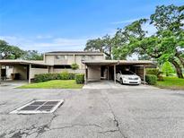 Inviting townhome showcasing a carport, manicured hedges, and mature trees under a bright blue sky at 8631 Cattail Dr, Temple Terrace, FL 33637