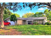 Charming single-story home featuring a well-kept lawn and vibrant landscaping, enhanced by mature trees and sunny skies at 1420 Citrus St, Clearwater, FL 33756
