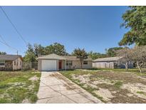 Charming single-story home with a driveway, attached garage, and a red front door at 7708 Belah Dr, New Port Richey, FL 34653