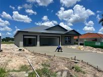 New construction home features a metal roof, gray stucco exterior, and a freshly poured concrete driveway at 24462 Cabana Rd, Punta Gorda, FL 33955