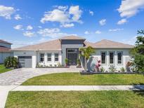 Beautiful single-story home featuring a well manicured lawn, brick paved driveway, and a welcoming front entrance at 8936 Sanders Tree Loop, Wesley Chapel, FL 33545