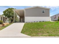 Well-maintained home with a covered parking area and a lush green lawn at 8857 Highpoint Blvd, Brooksville, FL 34613