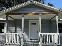 Charming home featuring a covered front porch with white railing and a welcoming front door at 8306 N Orleans Ave, Tampa, FL 33604