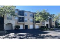 Beige condo building featuring private garages, screened in lanais, and lush landscaping at 5125 Palm Springs Blvd # 13107, Tampa, FL 33647
