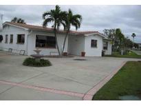 Charming single-story home featuring a spacious driveway, stucco siding, and mature palm trees at 17401 1St E St, Redington Shores, FL 33708