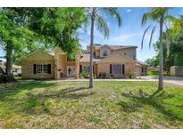 Two-story home with brick and siding exterior, complemented by palm trees and a well-manicured lawn at 20003 Holly Lake Pl, Lutz, FL 33558