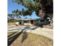 Charming single-story home featuring a vibrant red door and covered parking at 5428 Nutmeg Ave, Sarasota, FL 34231