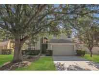 Charming two-story home with a well-manicured lawn, mature trees, and a two-car garage at 4432 Huddlestone Dr, Wesley Chapel, FL 33545