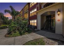 Inviting exterior view showcasing a red condominium building with lush landscaping and architectural details at 11901 4Th N St # 2107, St Petersburg, FL 33716