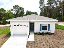 Charming single-story home featuring a well-manicured lawn, attached garage, and a welcoming blue front door at 8990 Glenarm Way, Weeki Wachee, FL 34613