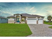 Beautiful single Gathering home featuring a lush green lawn and three-car garage with a brick driveway at 211 Rotonda S Blvd, Rotonda West, FL 33947