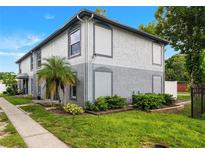 Two-story condo features a combination brick and stucco facade, a small palm tree, and manicured shrubs at 5112 Temple Heights Rd # B, Tampa, FL 33617