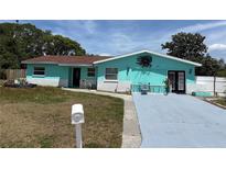 Charming single-story home with teal paint, a well-manicured lawn, and an inviting entrance, creating a welcoming curb appeal at 431 David Ct, Palm Harbor, FL 34684