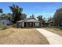 Charming home featuring neutral paint, contrasting trim, black shutters, a covered front porch, and ample natural light at 1819 E Humphrey St, Tampa, FL 33604