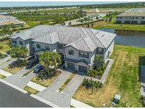 Beautiful aerial view of the gray townhomes, featuring lush landscaping and a tranquil pond in the background at 15242 Sunny Day Dr, Bradenton, FL 34211