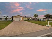 Charming single-story home with a brick driveway and well-maintained front yard, set against a beautiful sunset sky at 4043 Topsail Trl, New Port Richey, FL 34652