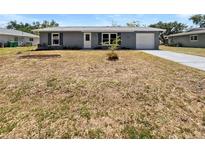 Charming single-story home with a well-maintained front yard, driveway, and attached garage at 837 Dolphin Nw Ave, Port Charlotte, FL 33948