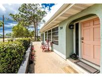 Charming home featuring a lovely, covered front porch with comfortable seating and an inviting coral-colored door at 70 Virginia Ct, Englewood, FL 34223