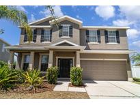 Charming two-story home featuring a well-maintained lawn, black shutters, and a two-car garage at 541 Vista Ridge Dr, Ruskin, FL 33570