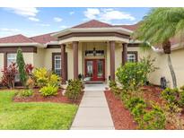 Charming single-story home with stucco exterior, a red tile roof, mature landscaping, and a covered front porch at 2818 Mossy Timber Trl, Valrico, FL 33596