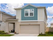 Two-story home featuring a two-car garage, covered porch and blue and tan color scheme at 34327 Verbena St, Wesley Chapel, FL 33545