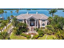 Stunning waterfront home with lush landscaping, beautiful water views, and a grand, columned entrance at 112 Osprey Point Dr, Osprey, FL 34229