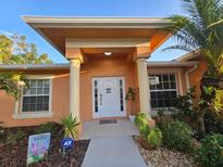 Inviting front entrance with charming welcome decor and manicured landscaping at 22227 Elmira Blvd, Port Charlotte, FL 33952