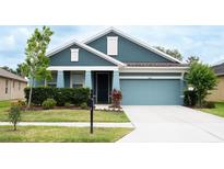 Charming single-story home with a well-manicured lawn and a light blue two-car garage at 32618 Rapids Loop, Wesley Chapel, FL 33545