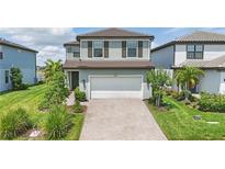 Charming two-story home with a well-maintained lawn, featuring a brick driveway and an attached two-car garage at 16231 Pine Mist Dr, Bradenton, FL 34211