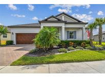 Charming home featuring a manicured lawn, mature landscaping, and a brick-paved driveway leading to a two-car garage at 31840 Magna Gulf Loop, San Antonio, FL 33576