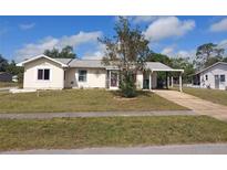 Charming single-story home with a well-manicured lawn, front tree, and a convenient carport at 4299 Bullard St, North Port, FL 34287