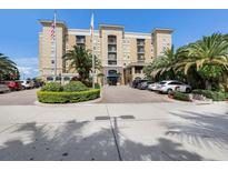 Beautiful tan apartment building featuring lush landscaping, palm trees, and prominent American flags at 1064 N Tamiami Trl # 1219, Sarasota, FL 34236