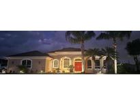 Charming single-story home featuring stucco exterior, a red front door, palm trees and manicured landscaping at 2668 Jablo Cir, North Port, FL 34288