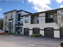 View of the residential apartment building featuring garages and balconies, complemented by lush landscaping at 8413 Lucuya Way # 306, Temple Terrace, FL 33637