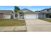 Charming single-Gathering home featuring a two-car garage, tidy lawn, and mature palm trees at 11114 Shadybrook Dr, Tampa, FL 33625