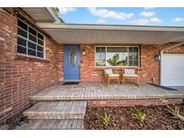 Charming brick home featuring a covered front porch with seating and a blue front door at 307 N Glen Ave, Tampa, FL 33609