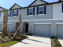 New two-story townhome with blue shutters and a one-car garage, complemented by palm trees at 32128 Eastern Redbud Br, San Antonio, FL 33576