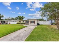 Charming single-story home with a well-manicured lawn, palm trees, and a white picket fence at 5710 92Nd N Ter, Pinellas Park, FL 33782