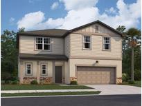 Two-story home featuring beige siding, a two-car garage, and manicured landscaping at 14673 Italy Ave, Dade City, FL 33523