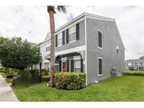 Two-story townhouse featuring a gray stucco exterior, black shutters, and a well-maintained front lawn at 232 Countryside Key Blvd, Oldsmar, FL 34677