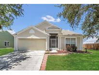 Charming single-story home featuring a two-car garage, well-maintained lawn, and mature trees at 205 Island Water Way, Apollo Beach, FL 33572