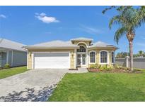 Charming home with a manicured lawn, lush landscaping and a white garage door at 6412 Coquina Island Cv, Apollo Beach, FL 33572
