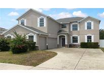 Two-story home featuring neutral stucco, white window trim, an arched entry, and a two car garage at 10768 Carloway Hills Dr, Wimauma, FL 33598