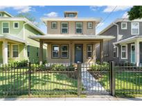 Charming two-story home with a well-manicured lawn and black metal fence at 3027 W Spruce St, Tampa, FL 33607
