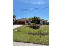 Charming single-story home features lush landscaping, a brown roof, and a two car garage at 8252 Tecumseh Cir, Port Charlotte, FL 33981