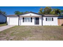Charming single-story home with a well-manicured lawn and a classic white facade at 9235 Richwood Ln, Port Richey, FL 34668