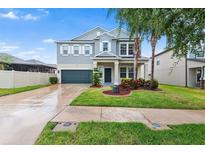 Two-story home featuring a well-manicured lawn, two-car garage, and charming front porch at 14095 Tropical Kingbird Way, Riverview, FL 33579