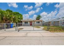 Charming single-story home featuring a red front door, chain-link fence, and inviting curb appeal at 4111 13Th S Ave, St Petersburg, FL 33711