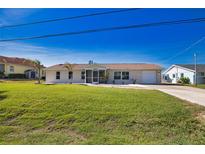 Charming single-story home with a well-maintained lawn and attached garage and screen front door at 1933 Oregon Trl, Englewood, FL 34224
